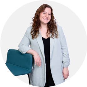 Frau mit dunklen Haaren und blauen Blazer l&auml;chelt in Kamera