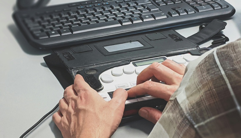 Zwei H&auml;nde bedienen eine Blinden-Tastatur