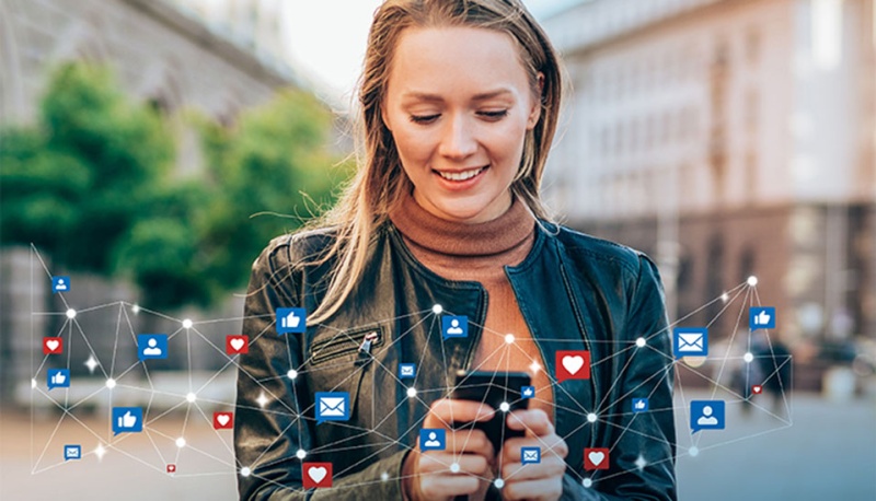 Eine Frau h&auml;lt Smartphone in der Hand und postet Nachrichten in sozialen Netzwerken