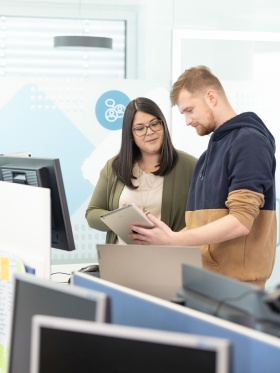 Zwei Personen betrachten in einem Büro einen Tablet-Computer.