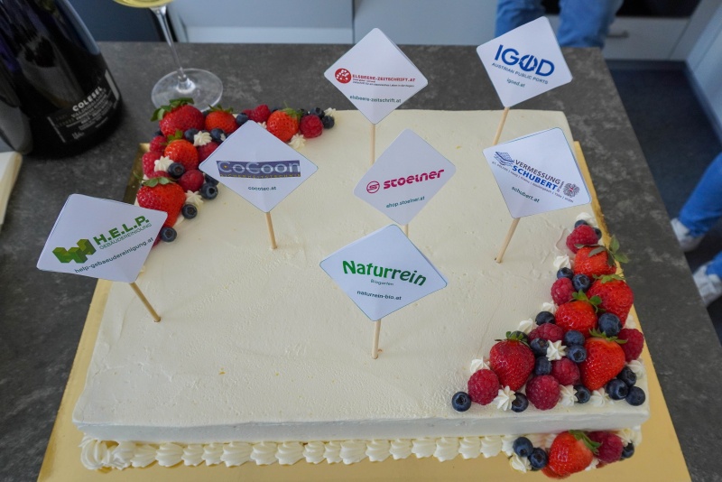 Torte mit Obstverzierung und Spießchen mit Kundenlogos darauf