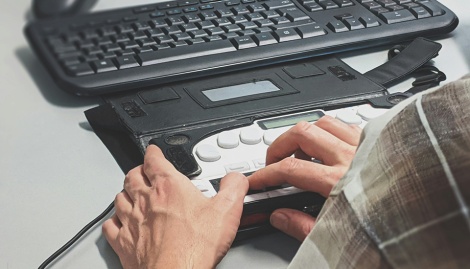 Zwei Hände bedienen eine Blinden-Tastatur
