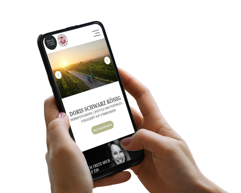 Hand h&auml;lt Smartphone, darauf ist ein Screenshot der Website zu sehen