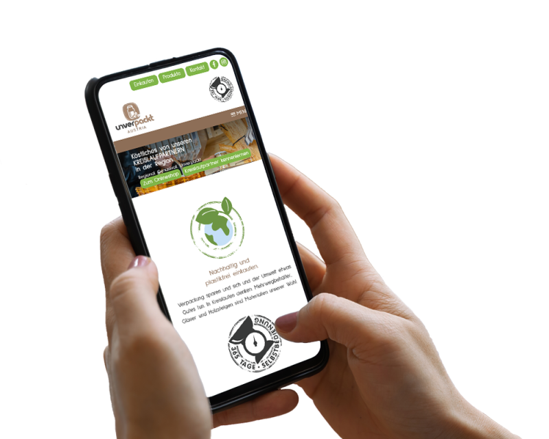 Hand h&auml;lt Smartphone, darauf ist ein Screenshot der Website zu sehen