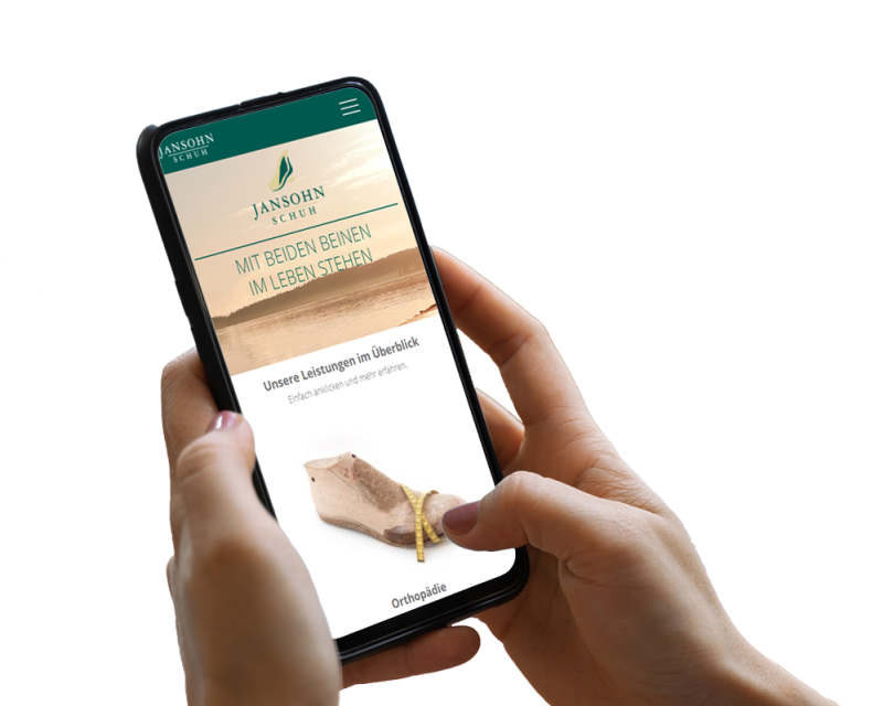 Hand h&auml;lt Smartphone, darauf ist ein Screenshot der Website zu sehen