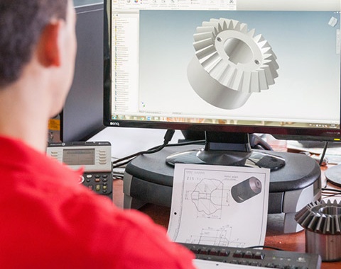 Ein Mann schaut sich am Computer einen Entwurf eines Bauteiles an.