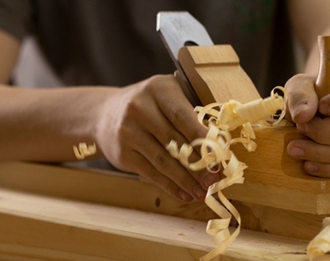 Hand hobelt ein St&uuml;ck Holz, Sp&auml;ne fliegen weg