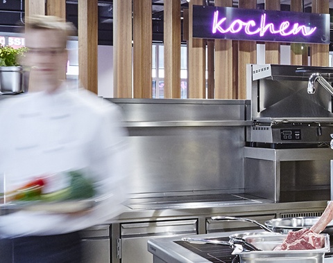 Verschwommen sichtbarer Kellner geht durch eine moderne Gastro-K&uuml;che.