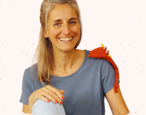 Sympathisches Portrait einer blonden Frau mit einer Sockenpuppe auf dem Kopf