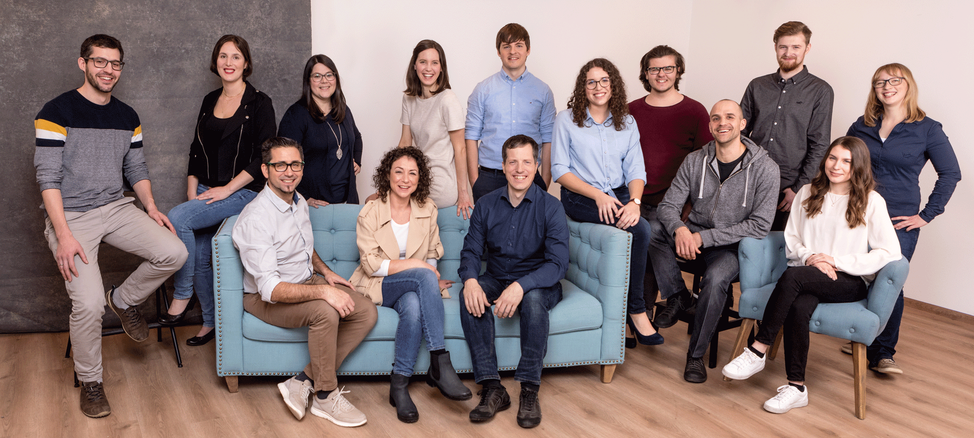 Bild: Doris Schwarz-König 14 Personen stehen, einige sitzen auf einer Couch. Alle lachen in die Kamera.