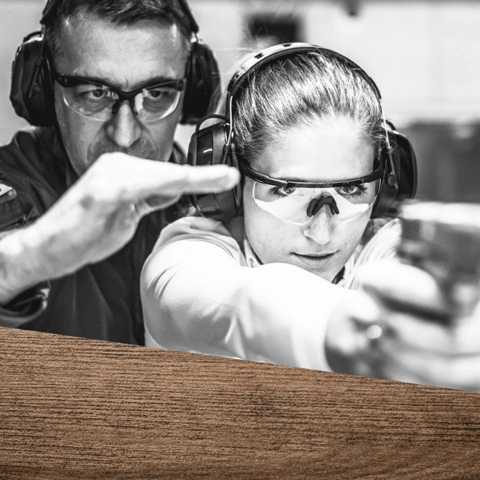 Eine Frau und ein Mann mit Schutzbrille und Gehörschutz üben das Zielen mit Pistole.