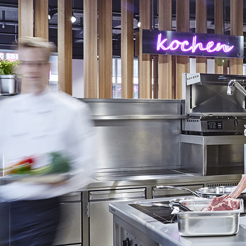 Verschwommen sichtbarer Kellner geht durch eine moderne Gastro-Küche.
